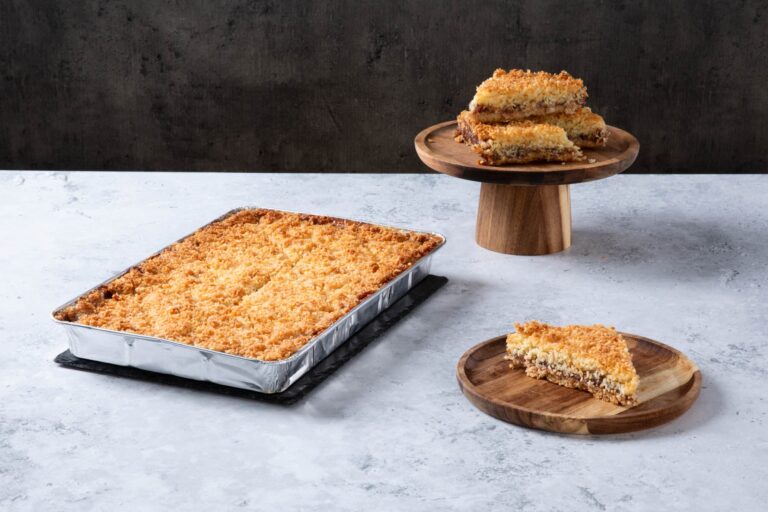 Chocolate cake with creamy frosting and chocolate topping on a wooden board.